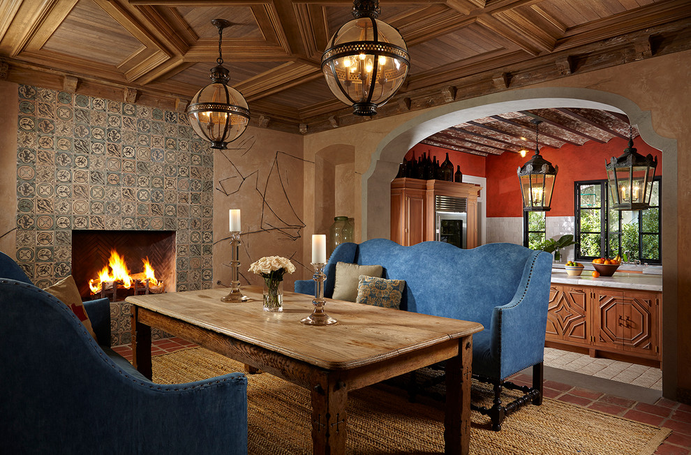 Idées déco pour une salle à manger méditerranéenne avec un mur beige, une cheminée standard, un manteau de cheminée en carrelage et un sol rouge.