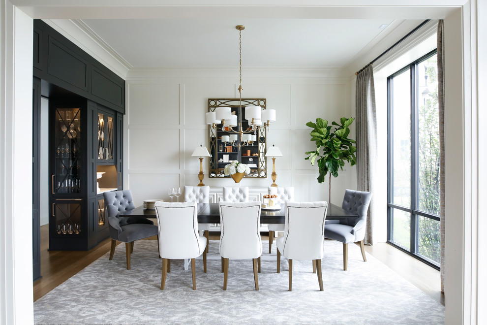 Immagine di una sala da pranzo classica chiusa con pareti bianche e parquet chiaro