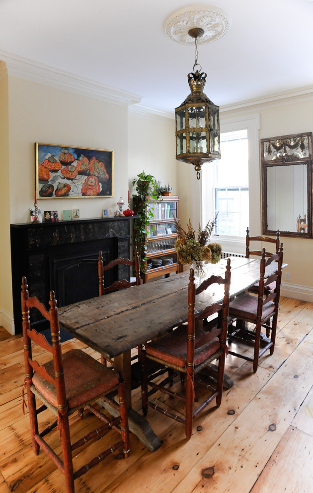 Immagine di una sala da pranzo chic con pareti beige, pavimento in legno massello medio e camino classico