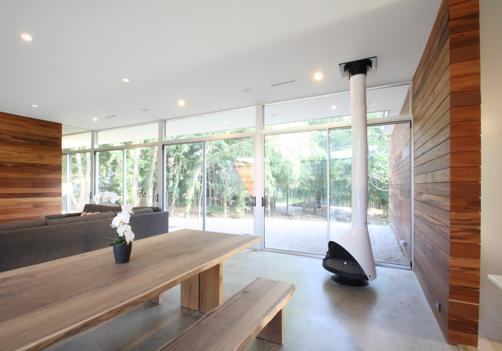 Esempio di una sala da pranzo moderna con pavimento in cemento e stufa a legna