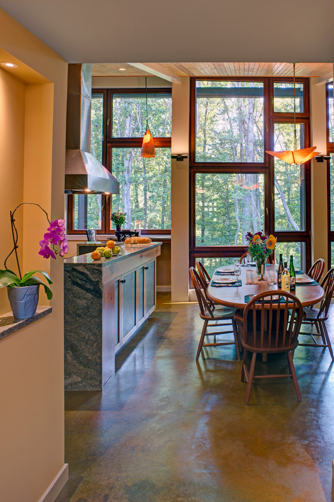 Example of a large mountain style concrete floor and multicolored floor kitchen/dining room combo design in Baltimore with yellow walls, a two-sided fireplace and a tile fireplace