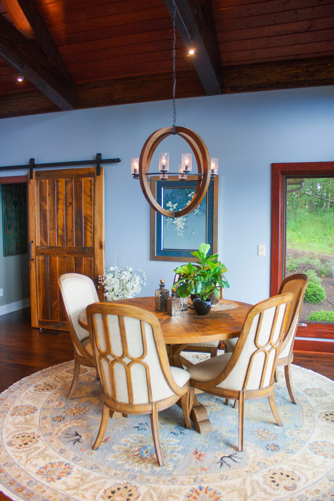 Cette image montre une salle à manger ouverte sur le salon design de taille moyenne avec un mur bleu, parquet foncé, une cheminée standard, un manteau de cheminée en pierre et un sol marron.