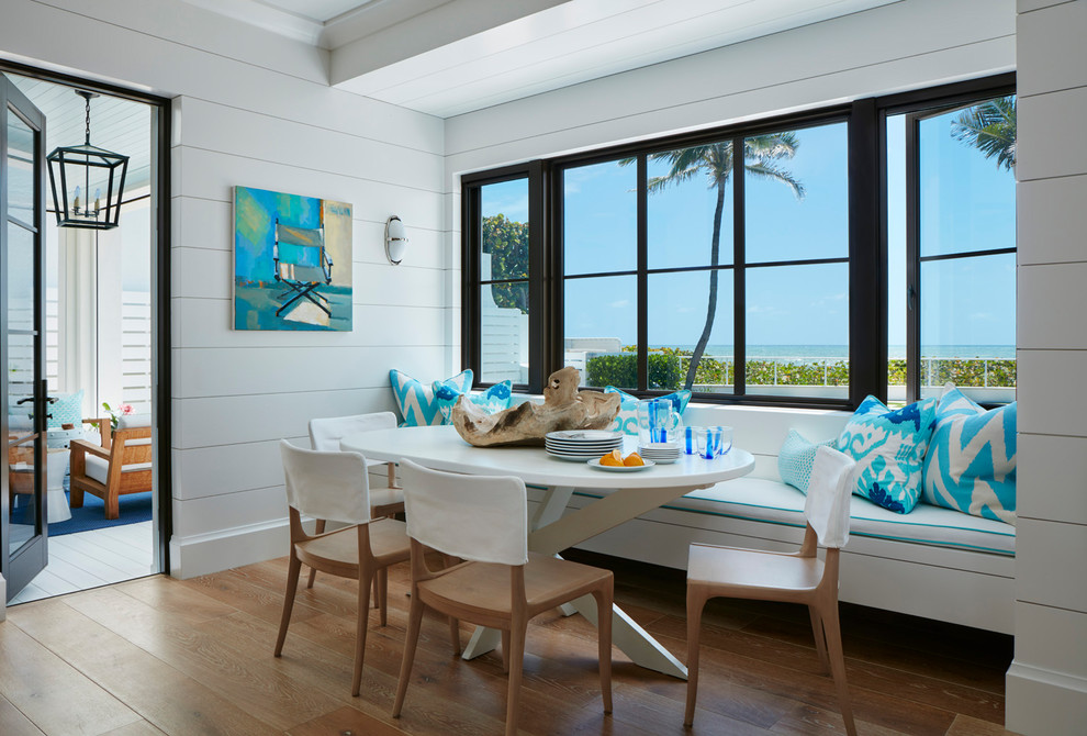 Inspiration for a beach style dining room in Miami with white walls and light hardwood flooring.