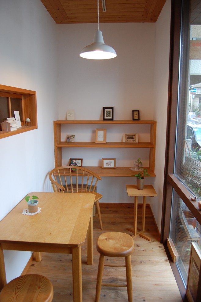 Cette photo montre une petite salle à manger nature avec un mur blanc, parquet clair et un sol marron.