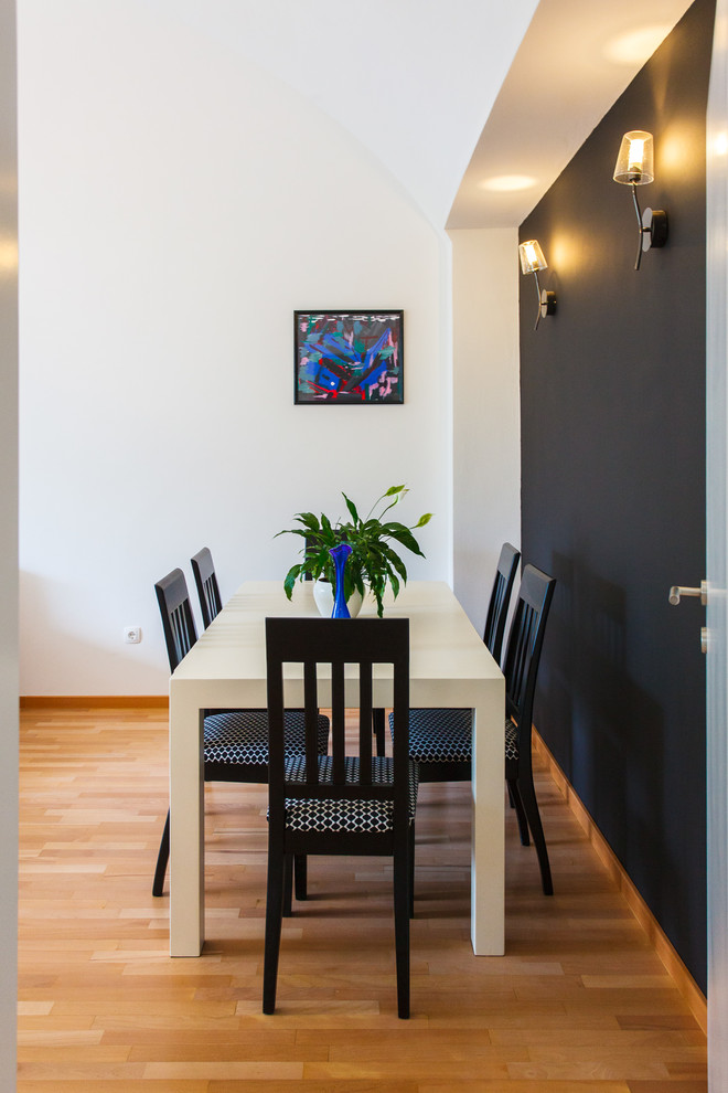 Kleines Modernes Esszimmer mit schwarzer Wandfarbe, braunem Holzboden und braunem Boden