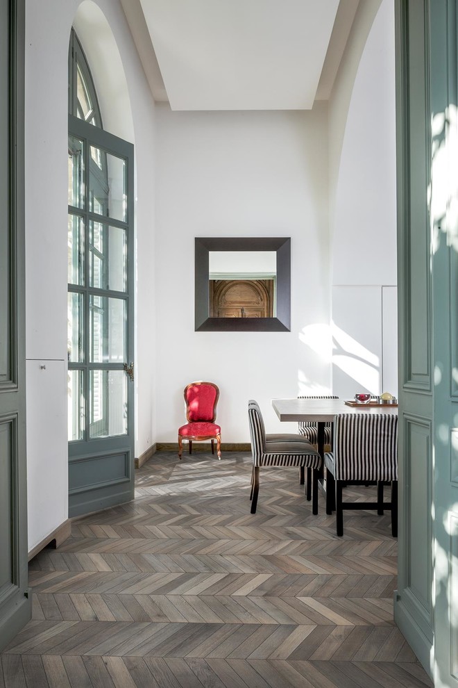 Imagen de comedor retro de tamaño medio cerrado con paredes blancas, suelo de madera en tonos medios y suelo gris