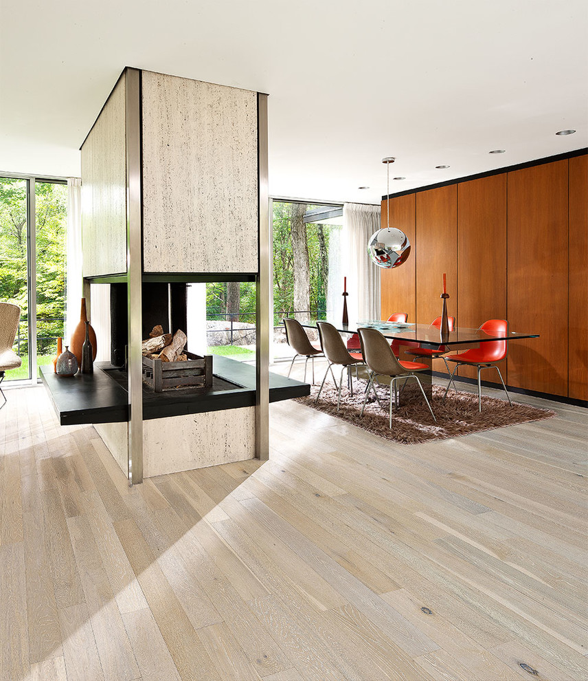 Foto di una sala da pranzo aperta verso il soggiorno minimalista di medie dimensioni con pareti marroni, pavimento in legno massello medio e camino bifacciale