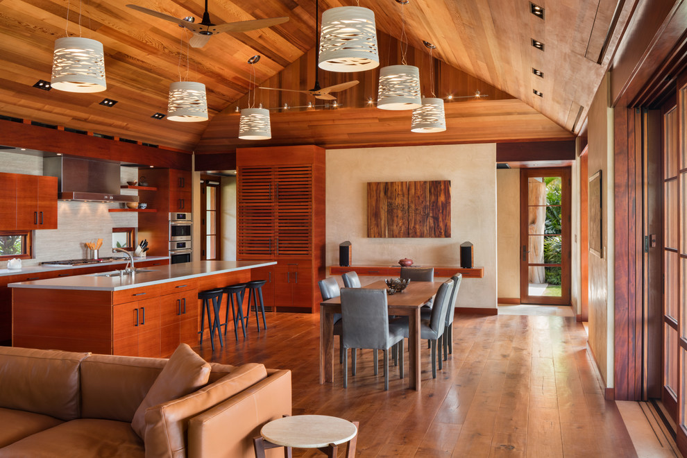 Esempio di una sala da pranzo aperta verso il soggiorno tropicale con pareti beige, parquet scuro e pavimento marrone