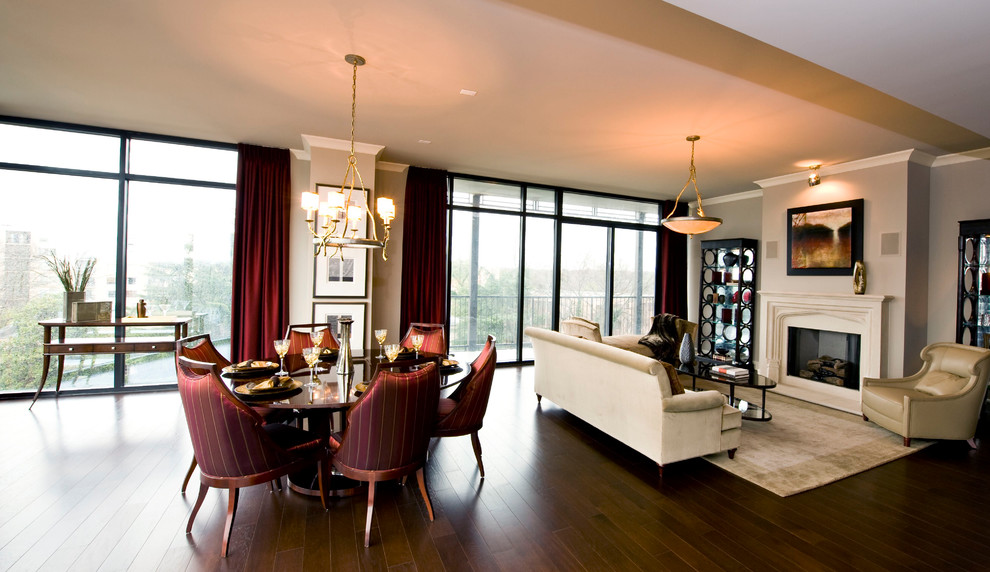 Cette photo montre une salle à manger ouverte sur le salon moderne de taille moyenne avec un mur beige, parquet foncé, une cheminée standard et un manteau de cheminée en plâtre.