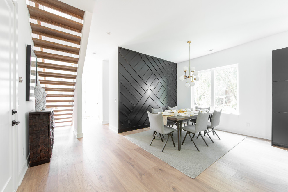 Cette photo montre une salle à manger ouverte sur la cuisine tendance avec un mur noir et sol en stratifié.