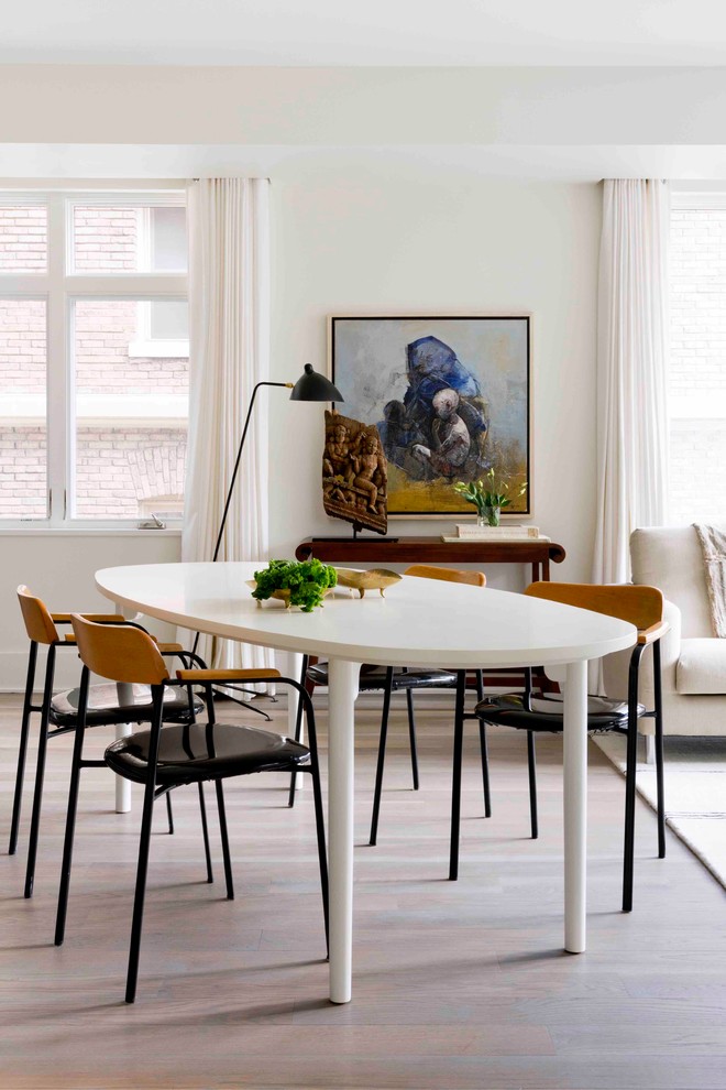Cette image montre une salle à manger ouverte sur le salon design avec un mur blanc, parquet clair et un sol beige.