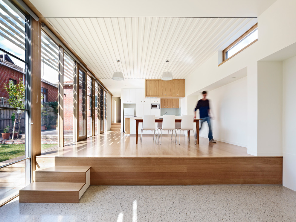Ispirazione per una sala da pranzo aperta verso la cucina minimalista con pareti bianche e pavimento in legno massello medio