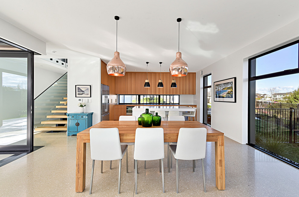 Esempio di una grande sala da pranzo aperta verso la cucina moderna con pareti bianche, pavimento in cemento e pavimento grigio