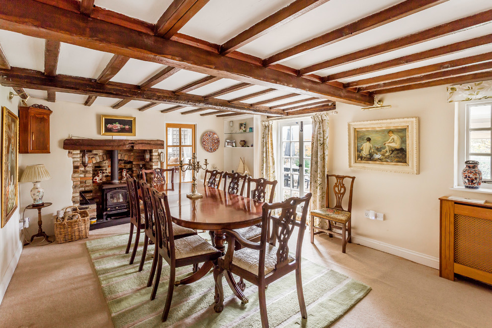 Country enclosed dining room in Surrey with white walls, carpet, a wood burning stove and a brick fireplace surround.