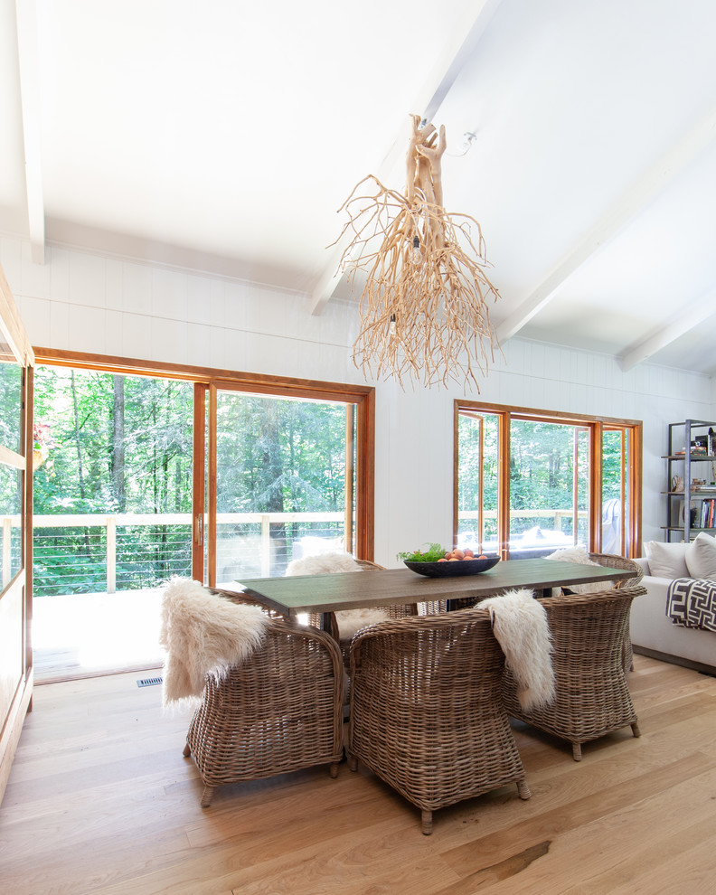 Rural open plan dining room in Charlotte with white walls, light hardwood flooring and beige floors.