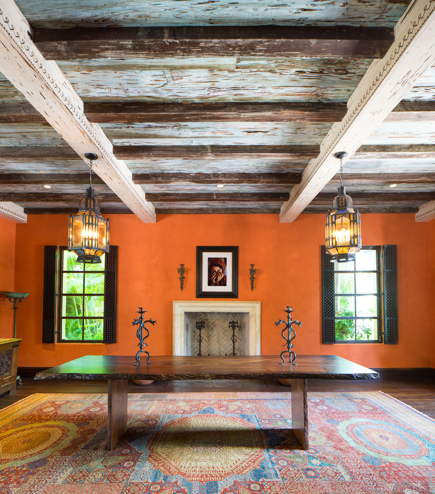 Стильный дизайн: большая гостиная-столовая в средиземноморском стиле с оранжевыми стенами, темным паркетным полом, стандартным камином, фасадом камина из камня и коричневым полом - последний тренд