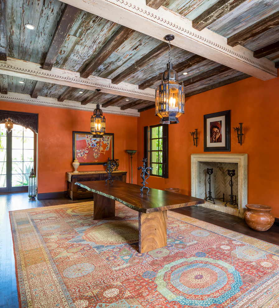 Свежая идея для дизайна: большая гостиная-столовая в средиземноморском стиле с оранжевыми стенами, темным паркетным полом, стандартным камином, фасадом камина из камня и коричневым полом - отличное фото интерьера