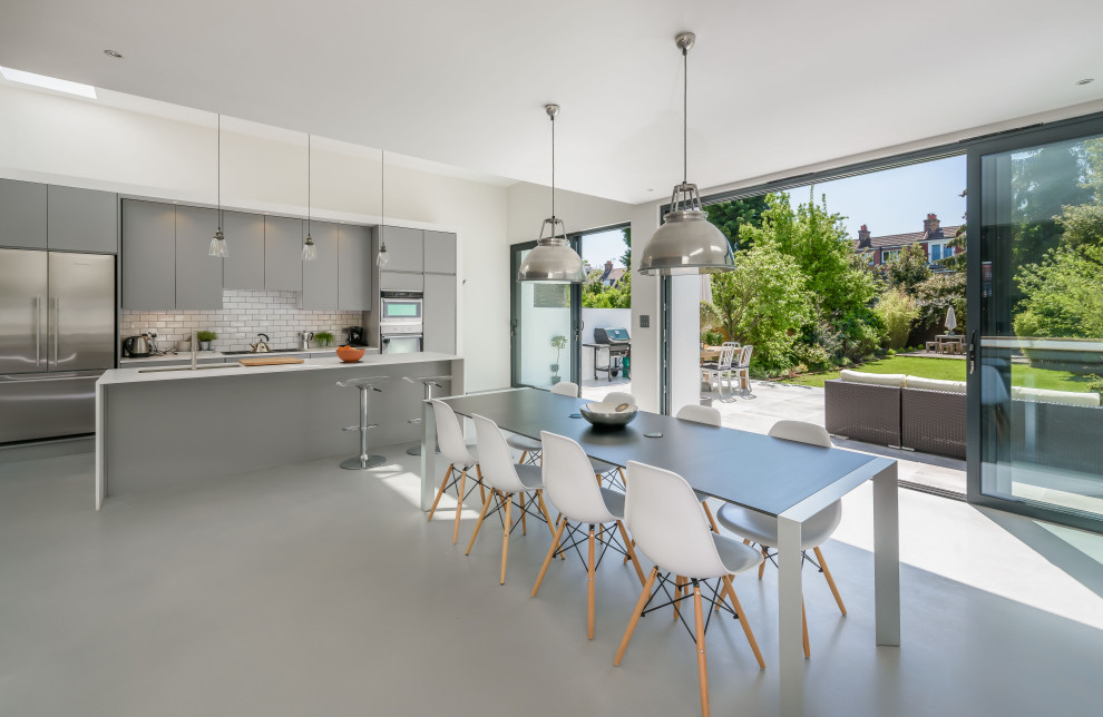 Cette image montre une salle à manger ouverte sur la cuisine design avec un mur beige, sol en béton ciré et un sol gris.