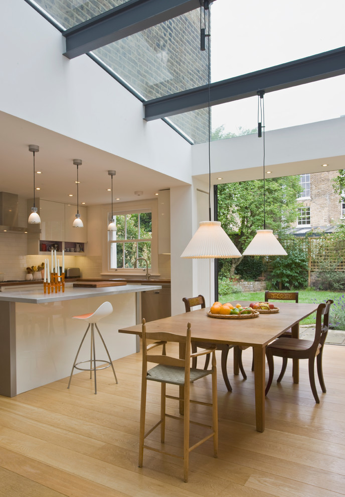 Photo of a contemporary kitchen/dining room in London with white walls and light hardwood flooring.