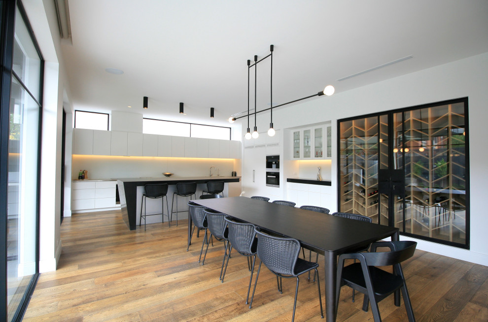Idée de décoration pour une grande salle à manger ouverte sur le salon design avec un mur blanc et un sol en bois brun.