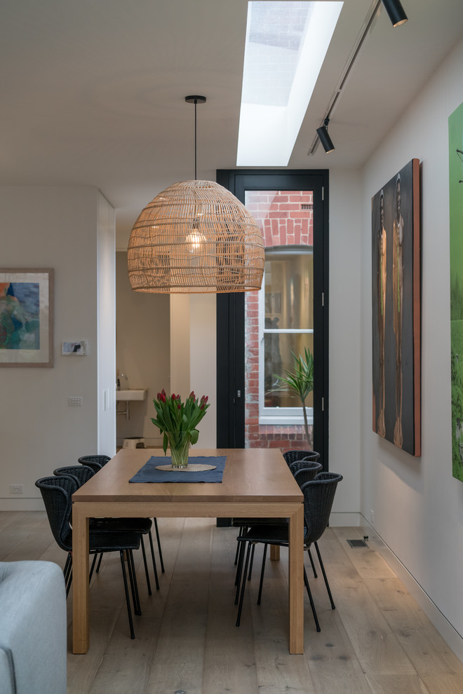 Réalisation d'une salle à manger ouverte sur le salon design avec un mur blanc, un sol en bois brun, un sol marron et éclairage.