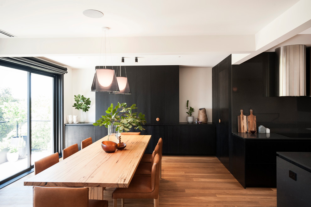 Réalisation d'une salle à manger ouverte sur le salon design de taille moyenne avec un mur blanc, un sol en bois brun, aucune cheminée et éclairage.