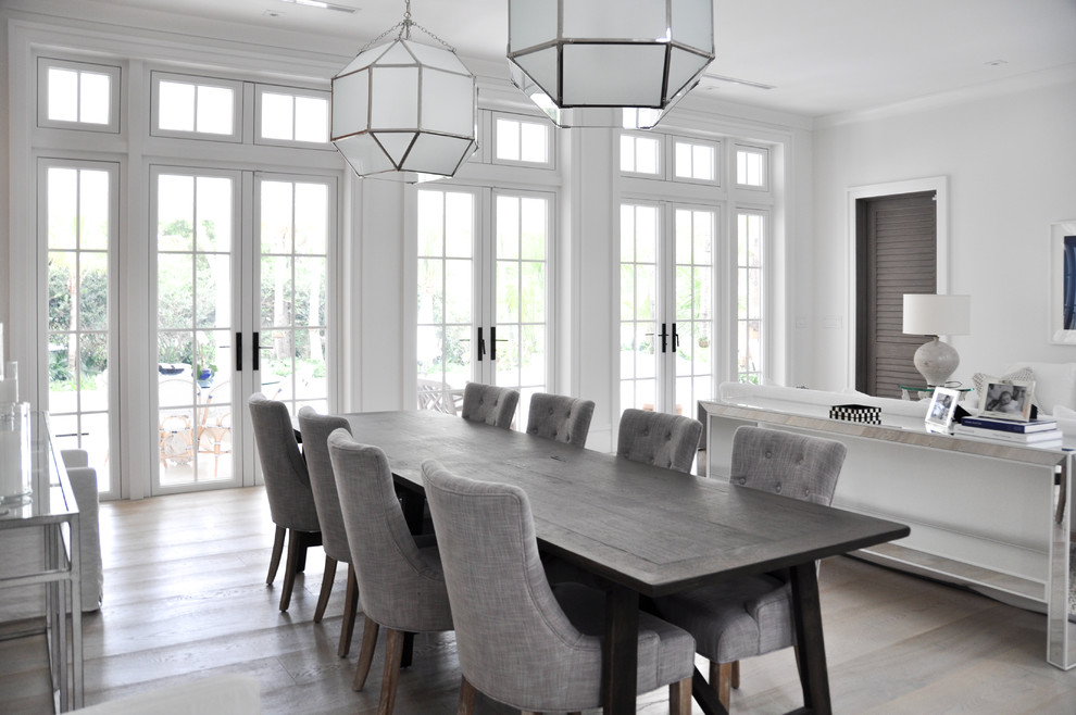 Immagine di una sala da pranzo aperta verso il soggiorno stile marinaro con pareti bianche e parquet chiaro
