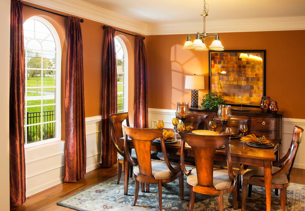 Ispirazione per una sala da pranzo classica chiusa e di medie dimensioni con pareti arancioni e pavimento in legno massello medio