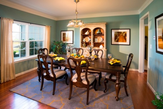 Exemple d'une salle à manger chic fermée et de taille moyenne avec un mur bleu, un sol en bois brun et éclairage.