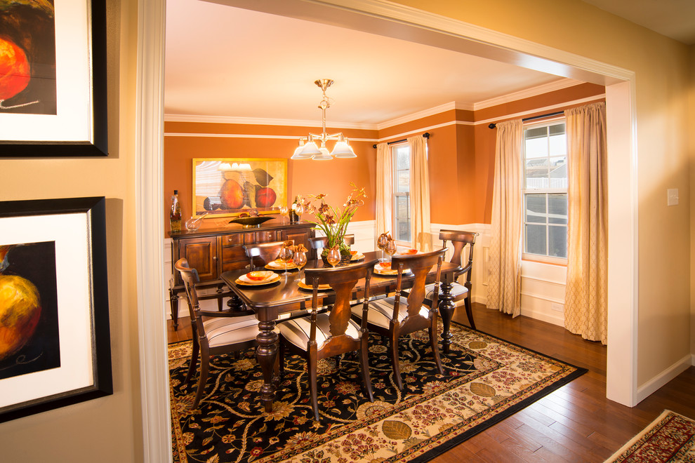 Immagine di una sala da pranzo tradizionale chiusa e di medie dimensioni con pareti arancioni e pavimento in legno massello medio