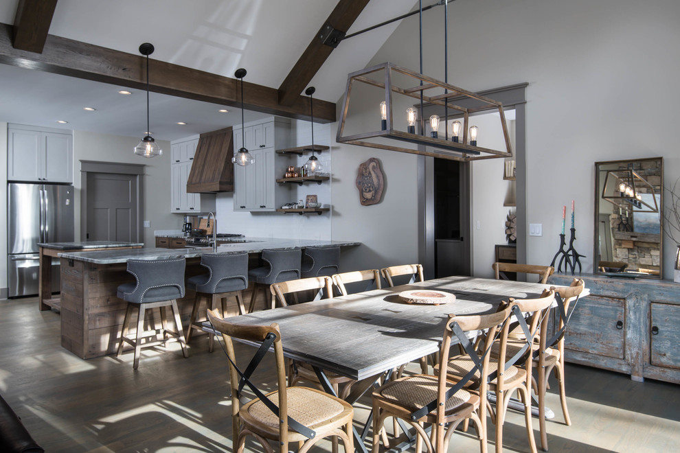 Aménagement d'une salle à manger ouverte sur la cuisine craftsman de taille moyenne avec un mur beige, un sol en bois brun, une cheminée double-face, un manteau de cheminée en pierre et un sol marron.