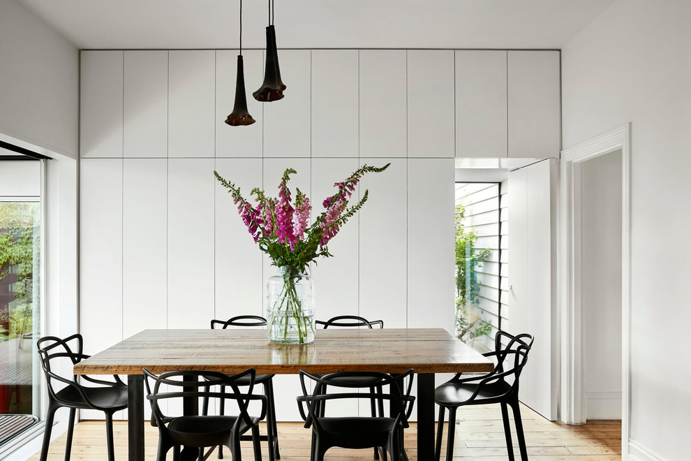 Inspiration pour une salle à manger design fermée avec un mur blanc et parquet clair.