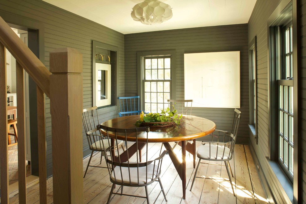 Aménagement d'une salle à manger campagne avec un sol en bois brun et un mur gris.