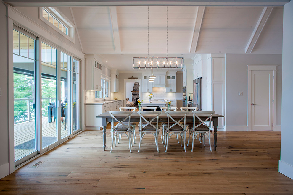 Idee per una sala da pranzo aperta verso il soggiorno stile americano di medie dimensioni con pareti bianche, pavimento in legno massello medio, camino classico e pavimento marrone