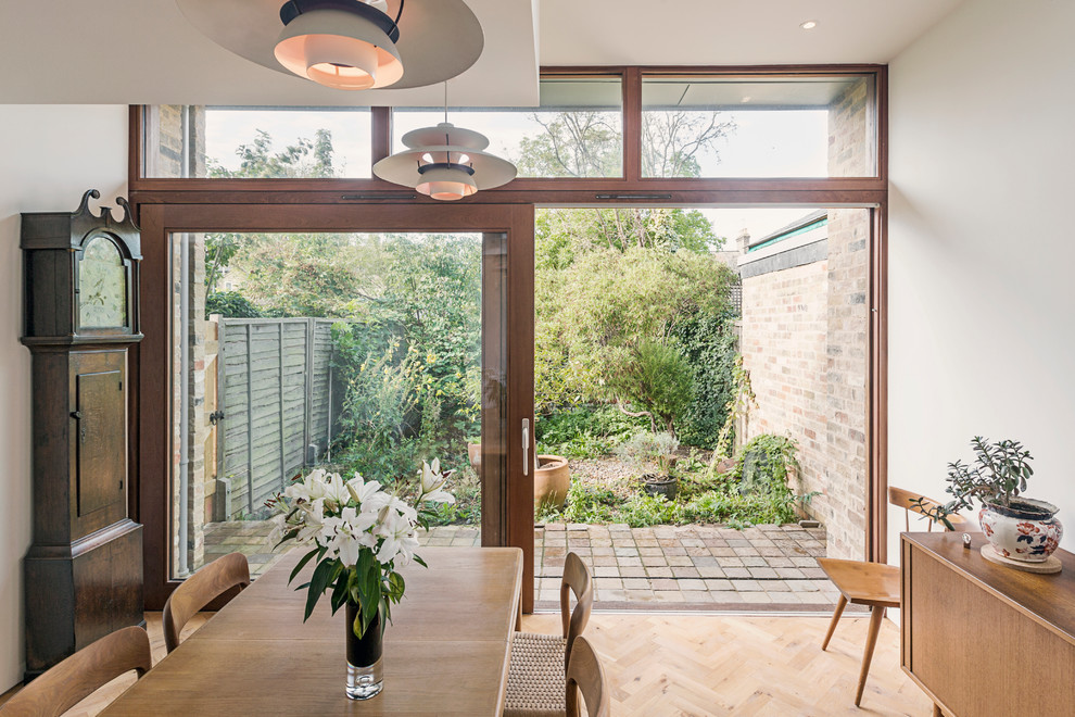 This is an example of a medium sized midcentury enclosed dining room in Cambridgeshire with white walls and light hardwood flooring.