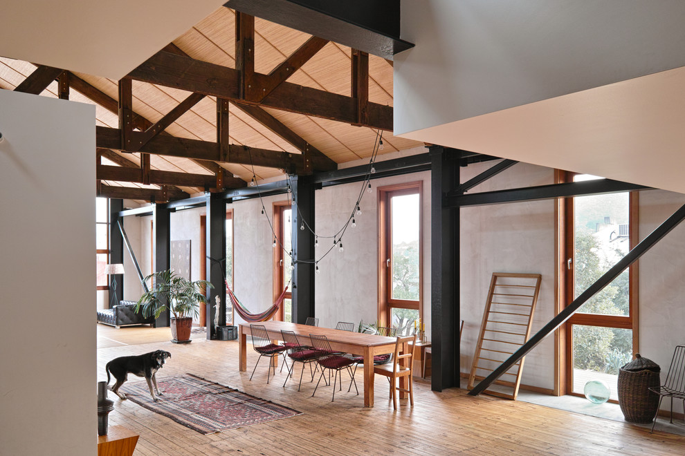 Aménagement d'une salle à manger ouverte sur le salon industrielle avec un mur gris et un sol en bois brun.
