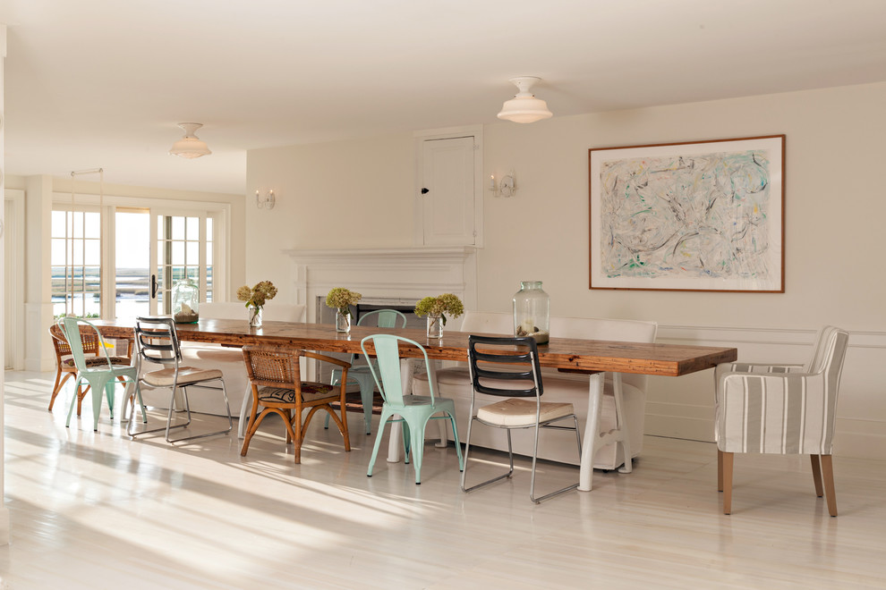 This is an example of a large farmhouse kitchen/dining room in Providence with white walls, a standard fireplace, a plastered fireplace surround, light hardwood flooring, white floors and feature lighting.