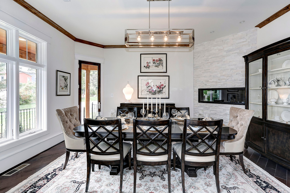 Cette photo montre une salle à manger ouverte sur le salon chic de taille moyenne avec un mur blanc, parquet foncé, une cheminée ribbon et un manteau de cheminée en pierre.