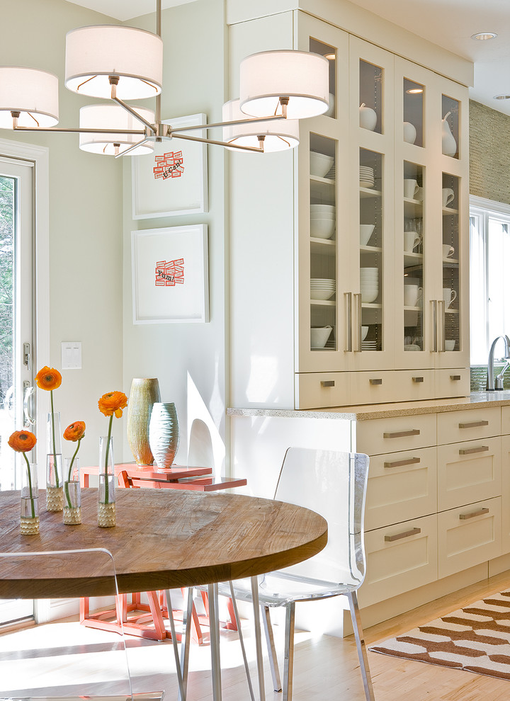 Foto di una sala da pranzo aperta verso la cucina minimalista con pareti bianche, parquet chiaro e nessun camino