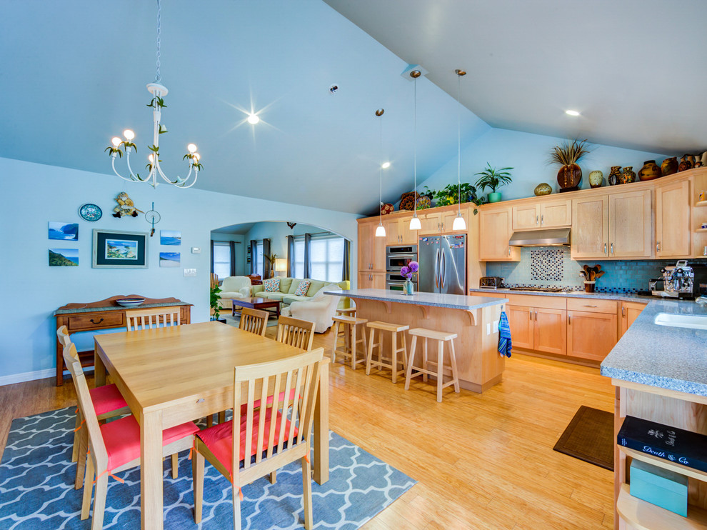 Foto di una grande sala da pranzo aperta verso la cucina con pareti blu e parquet chiaro