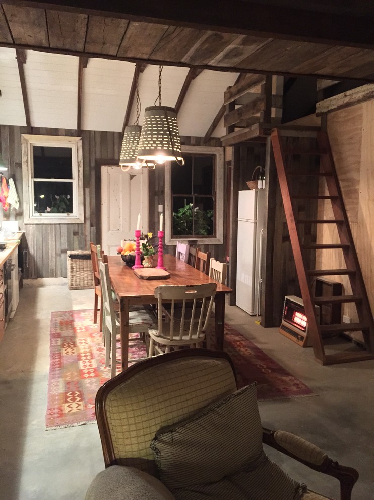 Foto di una piccola sala da pranzo aperta verso la cucina stile rurale con pavimento in cemento