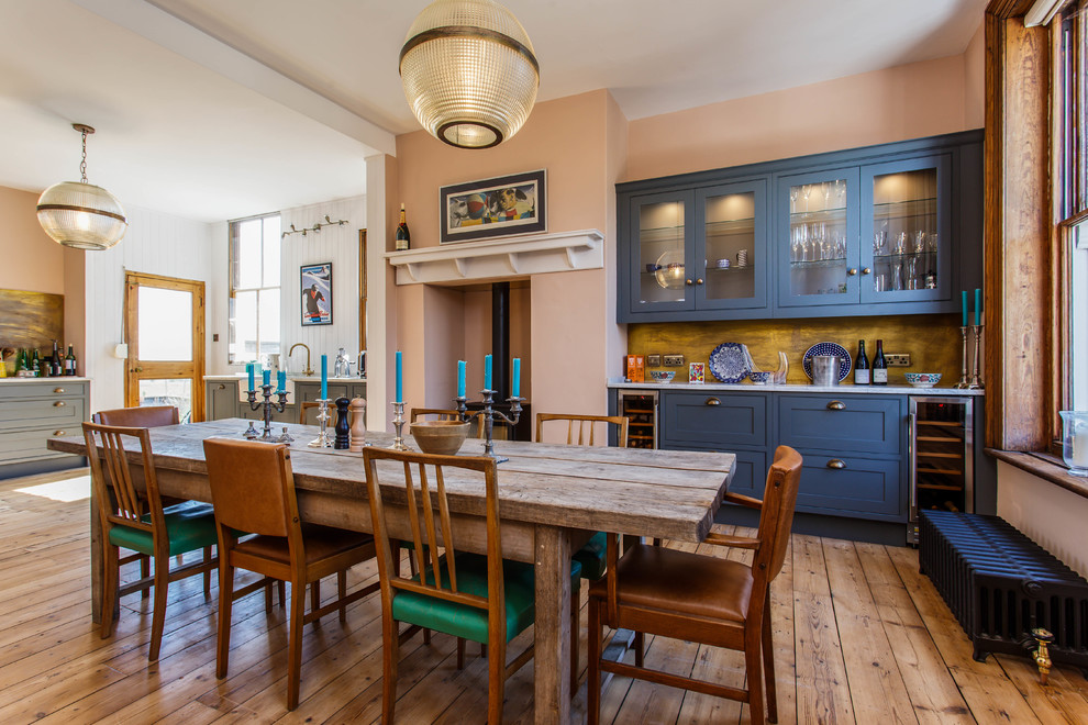 Exemple d'une grande salle à manger ouverte sur la cuisine éclectique avec un sol en bois brun, un mur orange, un poêle à bois et un sol marron.