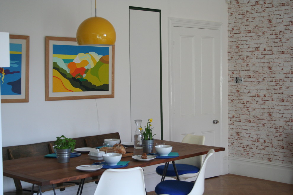This is an example of a large traditional open plan dining room in London with white walls and light hardwood flooring.