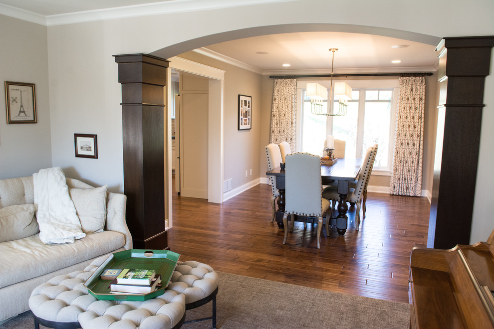 Exemple d'une salle à manger ouverte sur le salon chic de taille moyenne avec un mur gris, un sol en bois brun, un sol marron et aucune cheminée.