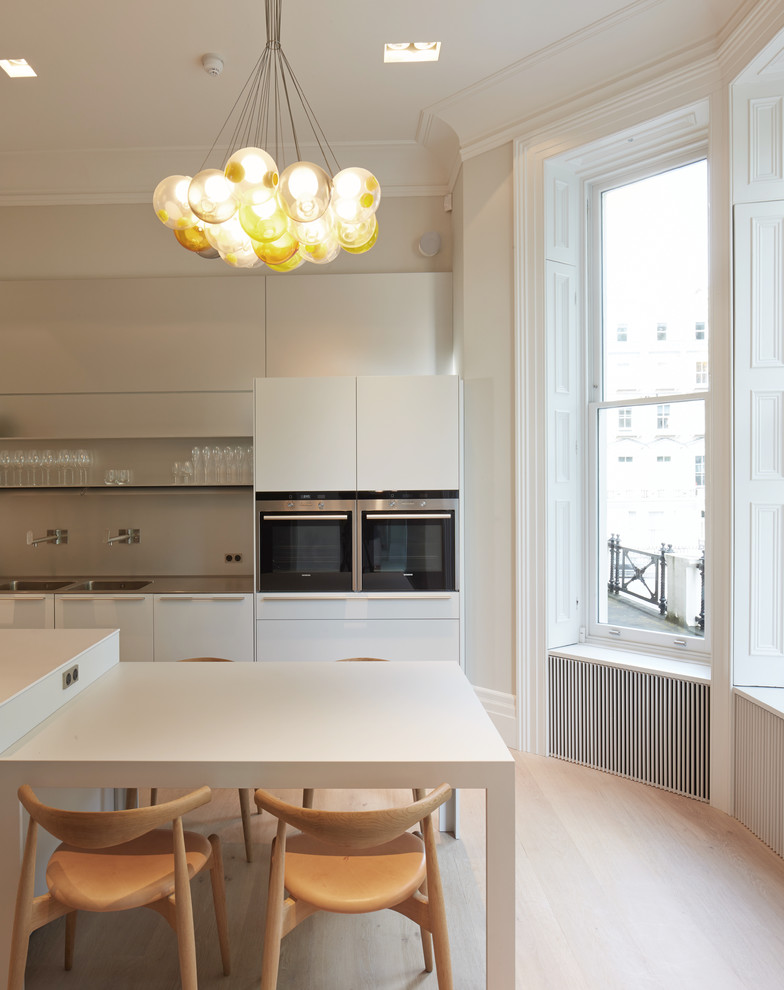 Idées déco pour une salle à manger ouverte sur la cuisine contemporaine de taille moyenne avec un mur gris et parquet clair.