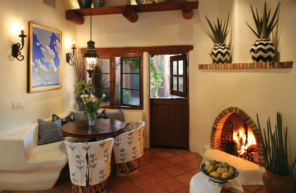 Modelo de comedor de estilo americano con paredes beige, chimenea de esquina y suelo de baldosas de terracota