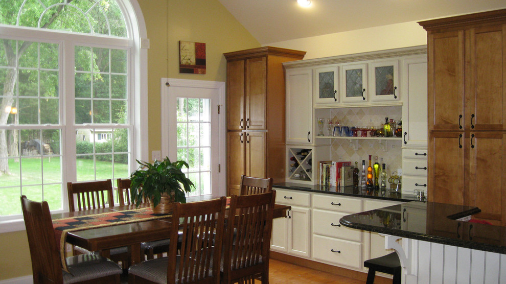 Immagine di un'ampia sala da pranzo aperta verso la cucina minimalista con pareti gialle e pavimento in legno massello medio