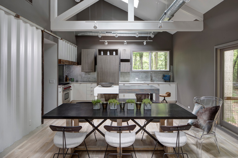 Ispirazione per una sala da pranzo aperta verso il soggiorno industriale con pareti grigie e parquet chiaro