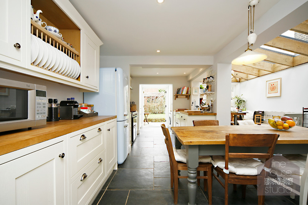 На фото: огромная кухня-столовая в стиле рустика с белыми стенами и полом из сланца