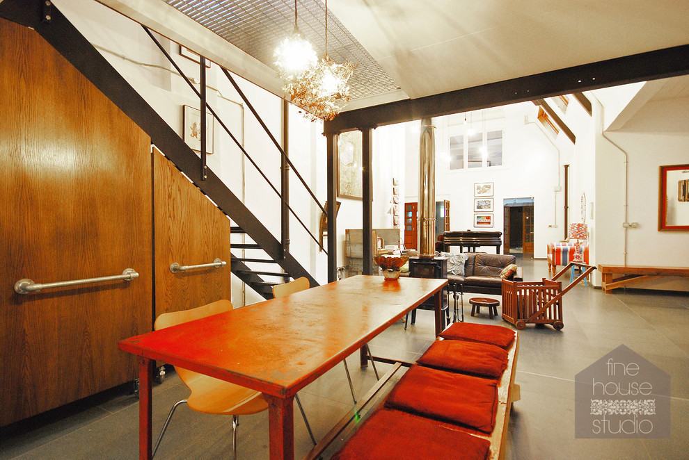 Immagine di un'ampia sala da pranzo aperta verso la cucina industriale con pareti bianche e pavimento in gres porcellanato